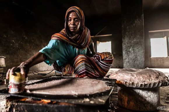 A Sudanese woman demonstrates how to make kisra, a traditional bread or porridge in Sudan and South Sudan. Photo by Mohamed Elfatih Hamadien, freely licensed under CC BY-SA 4.0.