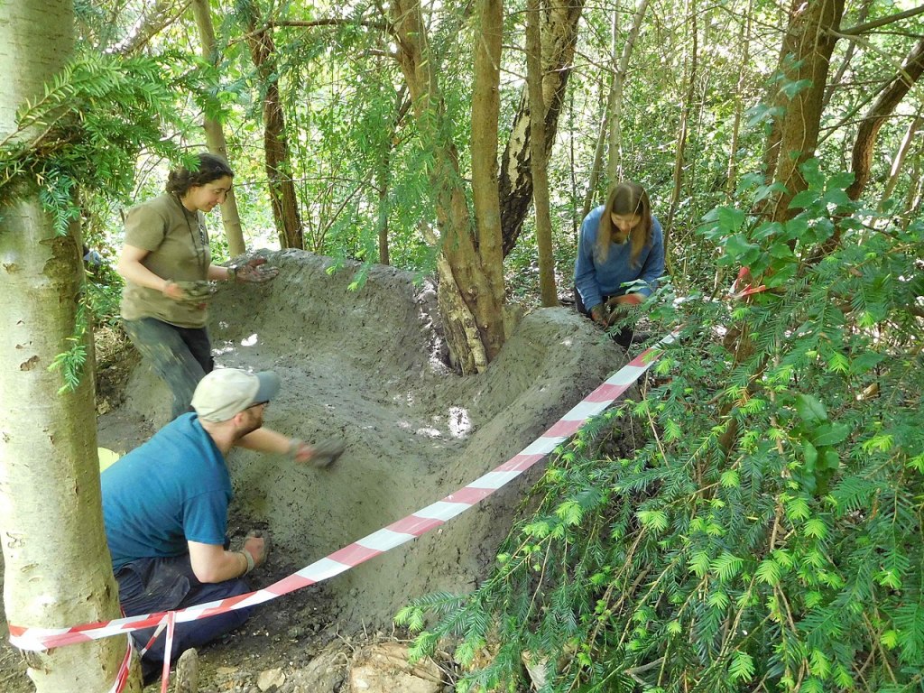 Staff and volunteers smoothing surface of mud sofa in Gunnersbury Triangle local nature reserve