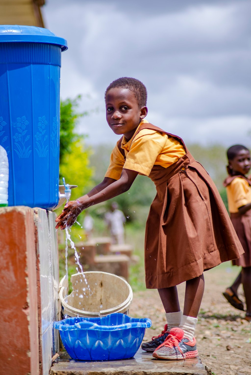 A pupil of New Weniba School Ghana washing her hands in respect to the Covid-19 protocol in the school