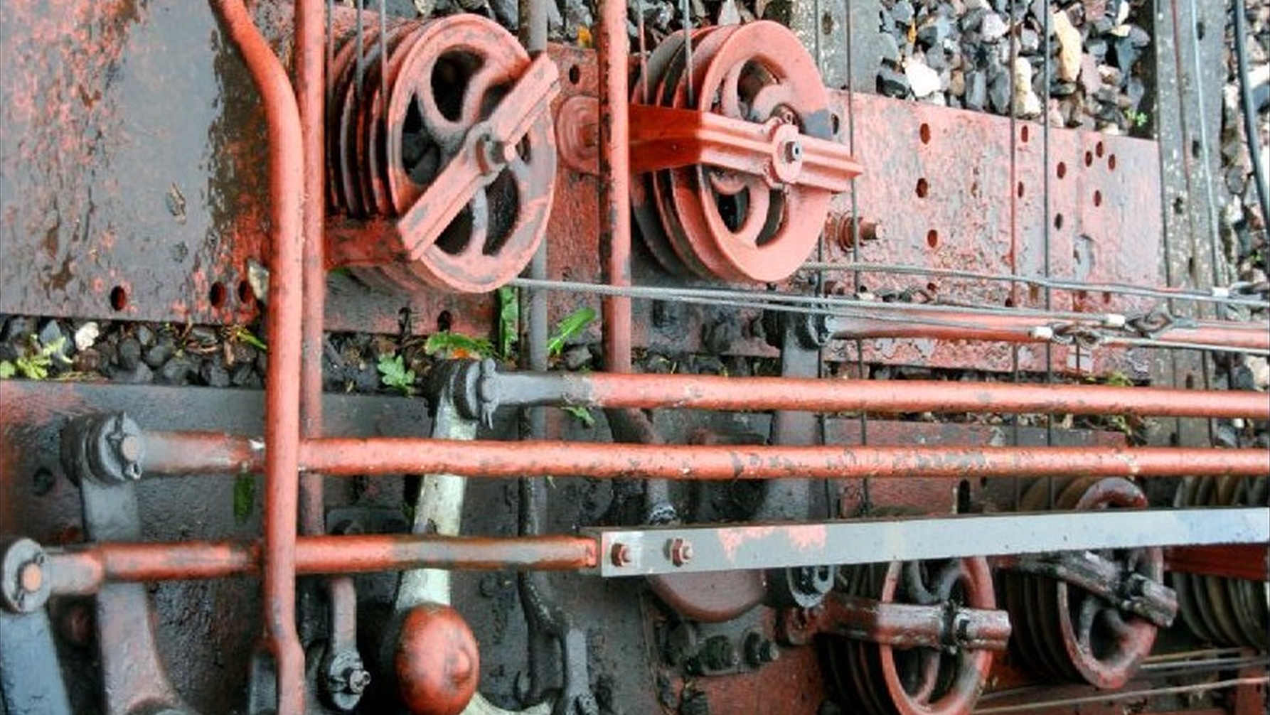 group of wheels, pulleys, levers and other rigid or semi-rigid transmission mechanisms, held together by wooden crosspieces, all placed on the ground on a bed of stones