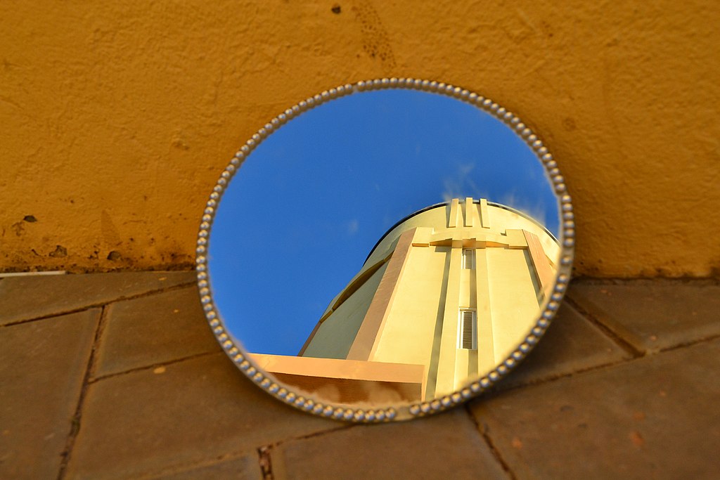 A decorative image showing a mirror that reflects a monument in Aruba