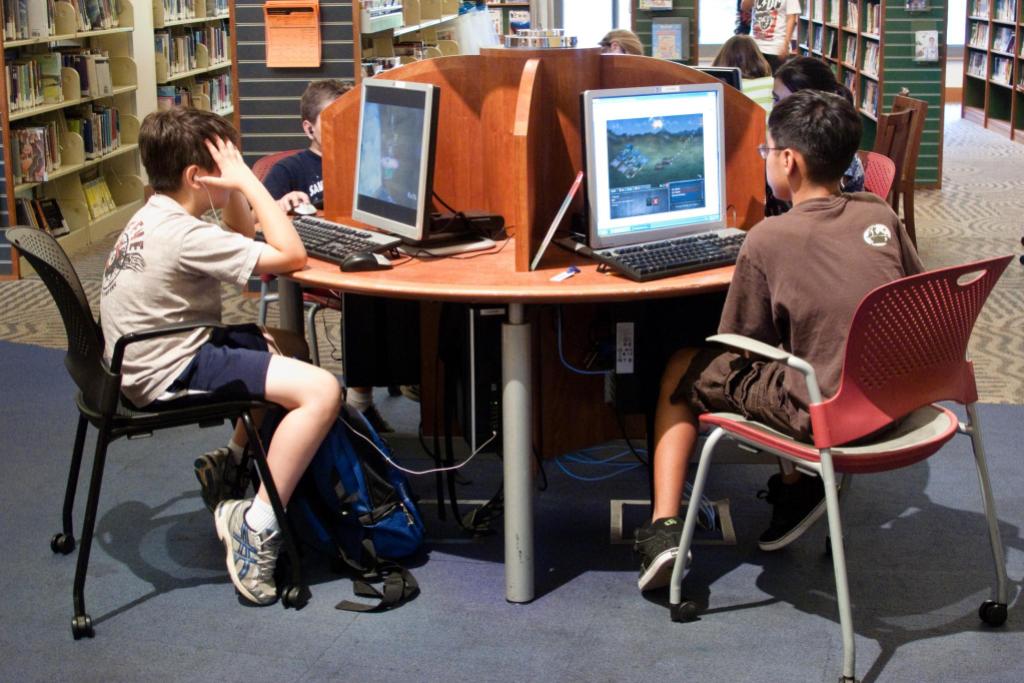 Children sitting at a computer station in a public library.