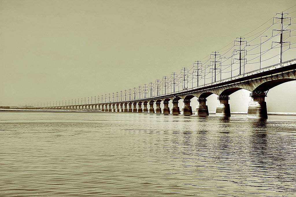 Bangabandhu Bridge, one of the longest bridges in the world, stretches into the distance filling the picture with water and the bridge with powerlines on top.