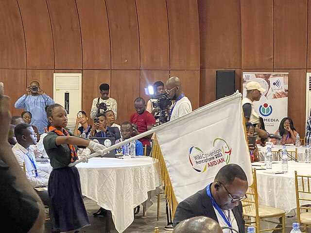 Présentation du drapeau de la WikiConvention Francophone 2023 par une Scout ivoirienne