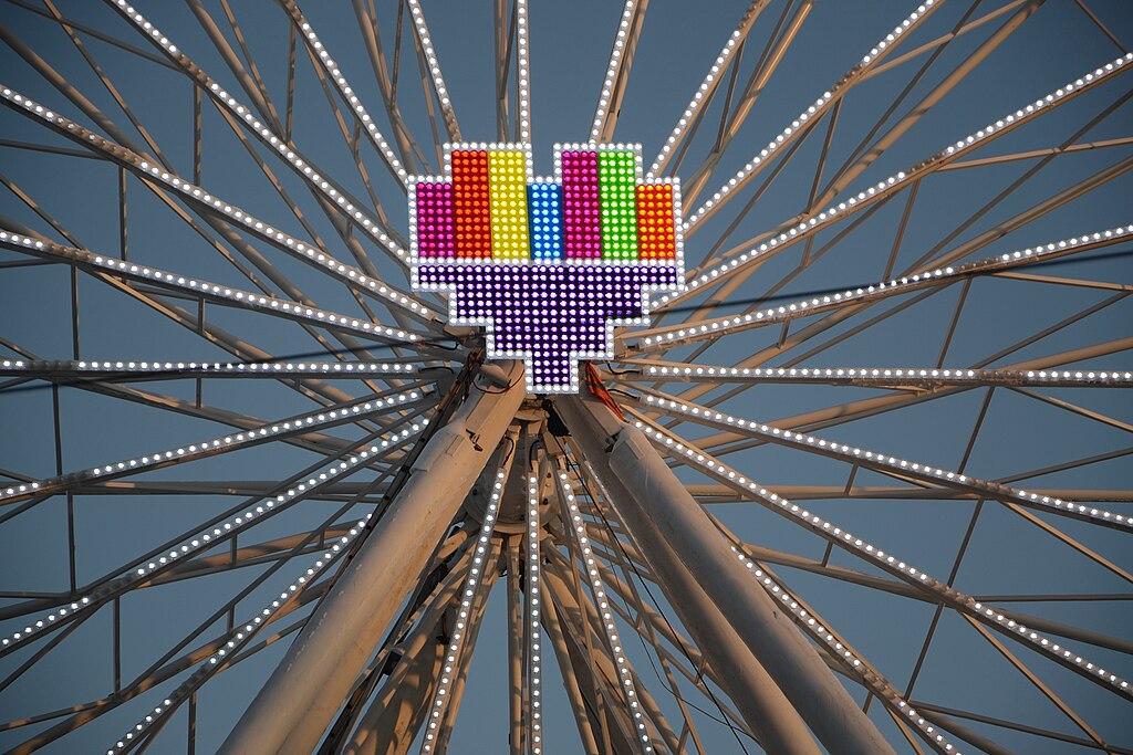 Image of a colorful pixel-style heart in the center of the spokes of a ferris wheel.